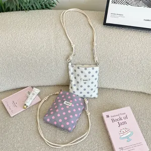 Lifestyle-detail van mini-crossbodytassen met stippen en verstelbare geknoopte riemen.