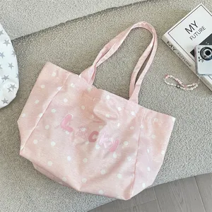 Detailed view of a sweet pink polka dot canvas tote bag featuring Lucky embroidery