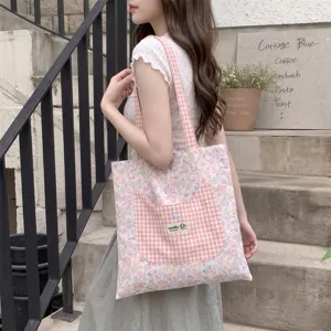 Model carrying a floral tote bag featuring a cute pink gingham cat-shaped pocket