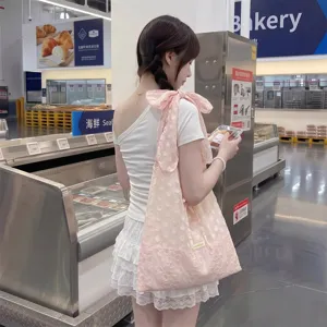 Vista detalle de un bolso tote de organza rosa con un gran lazo al hombro para mujer.