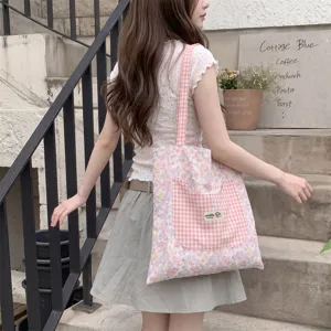 Student lifestyle detail of a pink floral tote bag with cat-shaped checkered pocket