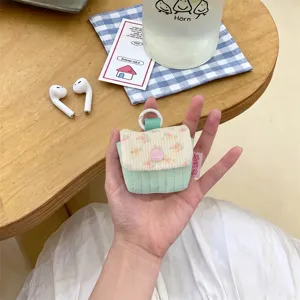 Primer plano de una linda funda de tela acolchada para auriculares con flores y broche.