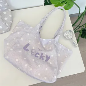 Close-up of a light purple polka-dot canvas tote bag with lucky letter embroidery