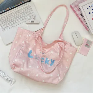 Close-up detail of the pink polka dot canvas tote bag with blue Lucky embroidery