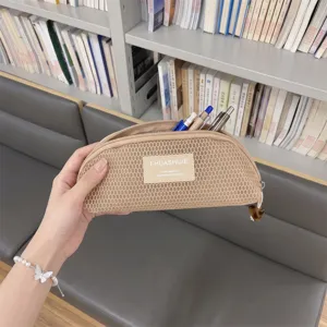 Macro view of a beige mesh shell-shaped pouch used as a portable stationery pencil case.