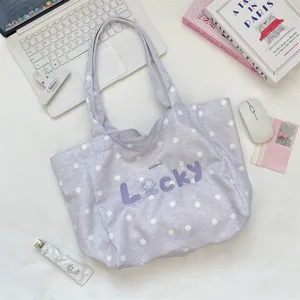 Detailed view of a purple polka dot canvas tote bag with 'LUCKY' embroidery.