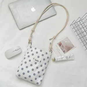 Detail van witte polka dot stoffen crossbody tas met verstelbare touwriem op bureau