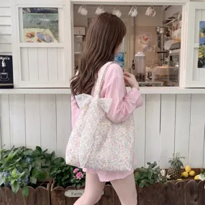 Detail view of a pink floral tote bag with a white lace bow carried by a girl in pink outfits.