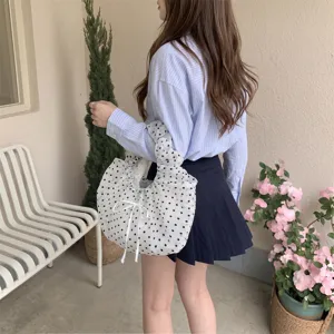 Detalle de un bolso de organza blanco con lunares negros y detalle de lazo de cinta.