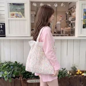 Floral print tote bag with large white lace bow accessory worn by model in cafe setting