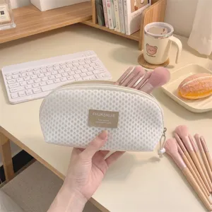 Portable shell-shaped mesh makeup brush storage bag with pink brushes close-up view.