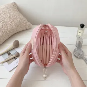 Detailed view of an open pink mesh shell-shaped makeup brush travel storage bag