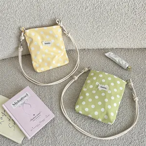 Detail van crossbodytassen met stippen en verstelbare geknoopte riemen in geel en groen