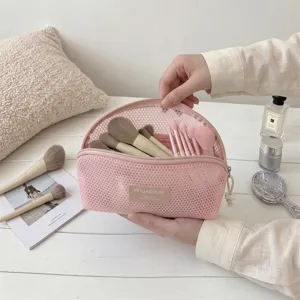 Detailed close-up showing a pink mesh makeup brush storage bag held with brushes inside