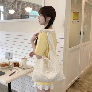 Detalle de bolso tote de organza con lunares blancos y correa de lazo grande.