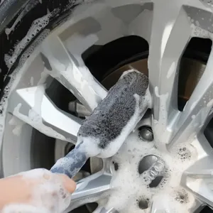 Primo piano di una spazzola in microfibra che pulisce i cerchioni dell'auto.