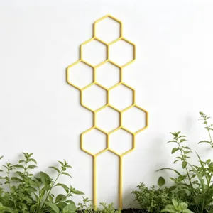 Detailed view of yellow honeycomb plant trellis supporting green potted plants in indoor garden.