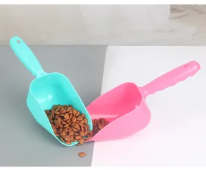 Gros plan detail de la pelle a nourriture pour animaux en plastique bleu et rose avec trou.
