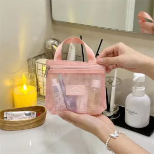 Detailansicht einer rosa Netz-Kulturtasche, die in einem modernen Bad gehalten wird
