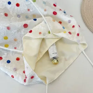 Detailansicht der bunten gepunkteten Stofftasche mit Innenfutter und Kosmetiktube.