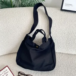 Bolso tote de lona negra con correa ancha para el hombro y accesorios de estilo artístico