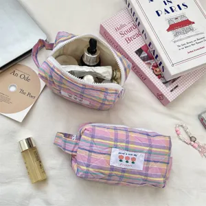 Close-up detail of plaid quilted cosmetic storage bag showing zipper and soft texture
