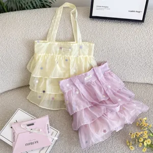 Vista detallada de los bolsos tote de organza con volantes y flores bordadas