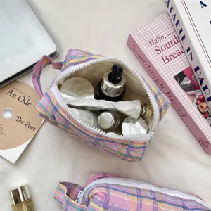 Macro view of colorful quilted plaid makeup organizer bag filled with beauty essentials.