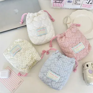 Primer plano de cuatro bolsas acolchadas con cordón y patrón de corazón para maquillaje.