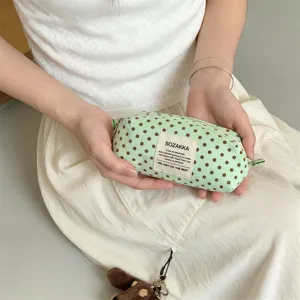 Detailed close-up of a mint green polka dot canvas makeup bag being held in hands