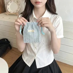 Close-up of a delicate light blue lace drawstring pouch held by a person