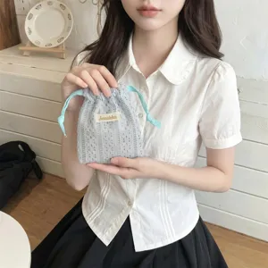 Girl holding a grey hollow lace drawstring bag for cosmetic storage in a cafe setting