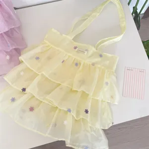 Vista detallada del bolso de organza amarilla con capas de volantes y bordado floral