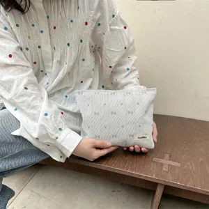 Close-up detail of heart and butterfly embroidery on a Japanese style grey cosmetic bag