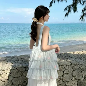 Detalle de los volantes de organza y bordado de mariposas en un entorno de playa exterior