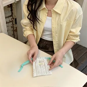 Close-up of a Japanese style off-white hollow lace drawstring storage pouch held by hands