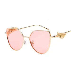 Stylish retro sunglasses featuring golden relief wings and trendy pink tinted lenses