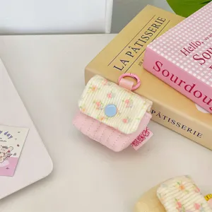 Detalle de una funda acolchada rosa con flores para auriculares y cierre de presión