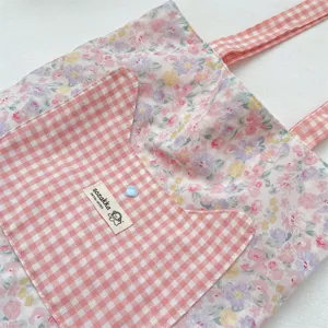 Close-up of pink floral canvas tote bag featuring a gingham cat-shaped pocket