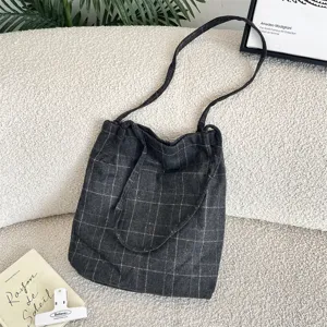 Close-up of a vintage dark gray plaid canvas tote bag with long shoulder straps.