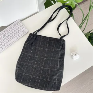 Close-up of a dark gray plaid vintage tote bag on a minimalist white desk setup