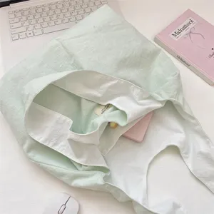 Detailansicht einer makronengrünen Canvas-Tragetasche mit weißem Futter und Label