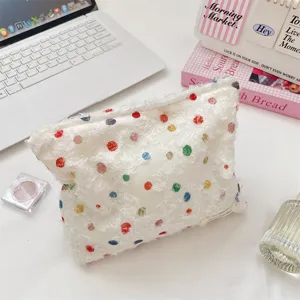 Detailopname van een witte organza make-uptas met kleurrijke stippen.