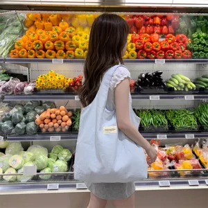 Detailansicht einer hellblauen Canvas-Einkaufstasche, getragen in einem Supermarkt