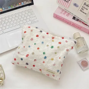 Gedetailleerd zicht op witte organza make-up tas met kleurrijke stippen en franjes