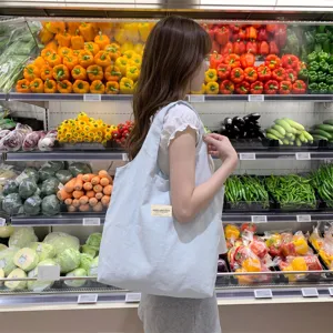 Große hellblaue Canvas-Tragetasche in einer Supermarkt-Lifestyle-Einkaufsszene.