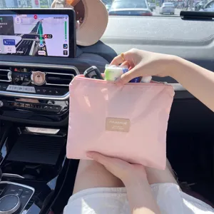 Roze draagbare opbergtas met rits voor make-up en accessoires in een auto-interieur