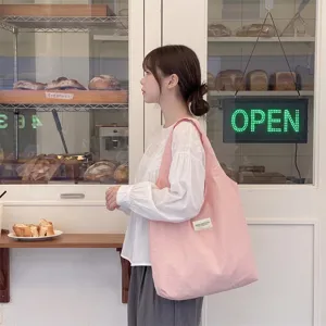 Model mit einer großen rosa Makronen-Canvas-Einkaufstasche in einer stilvollen Bäckerei