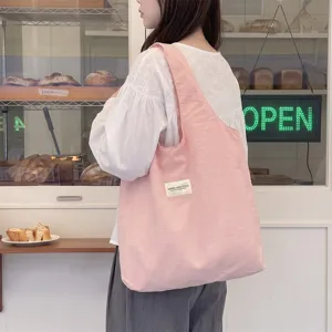 Große Canvas-Tragetasche in Makronenrosa, von einem Model in einer Bäckerei getragen