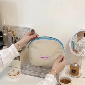 Detailweergave van een halfronde beige make-uptas met blauwe bies in een ijdelheidsscène